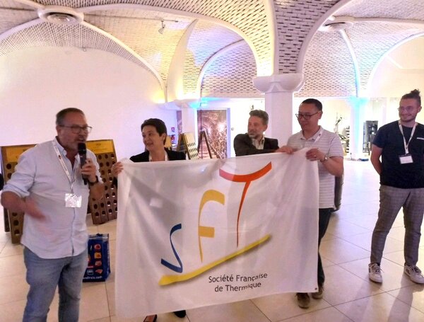 Participants tenant le drapeau de la SFT lors de la passation du Congrès Français de Thermique 2024