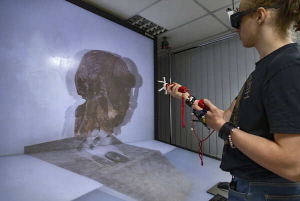 Personne utilisant un dispositif de réalité virtuelle devant un mur géant de visualisation dans le cadre des activités de la plateforme GAIA
