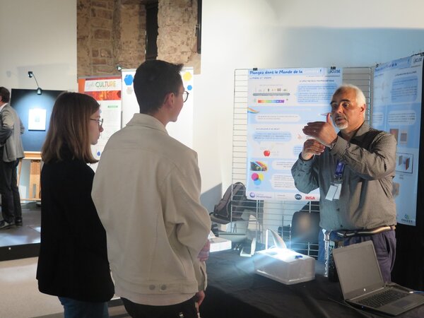 Mustapha Remouche animant un atelier pédagogique sur la lumière devant des visiteurs lors du festival Alsascience